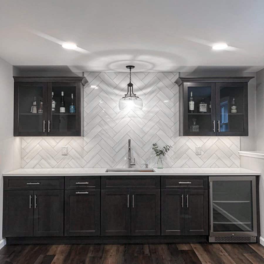 A contemporary kitchen with dark wood floors and cabinets with wine bottles