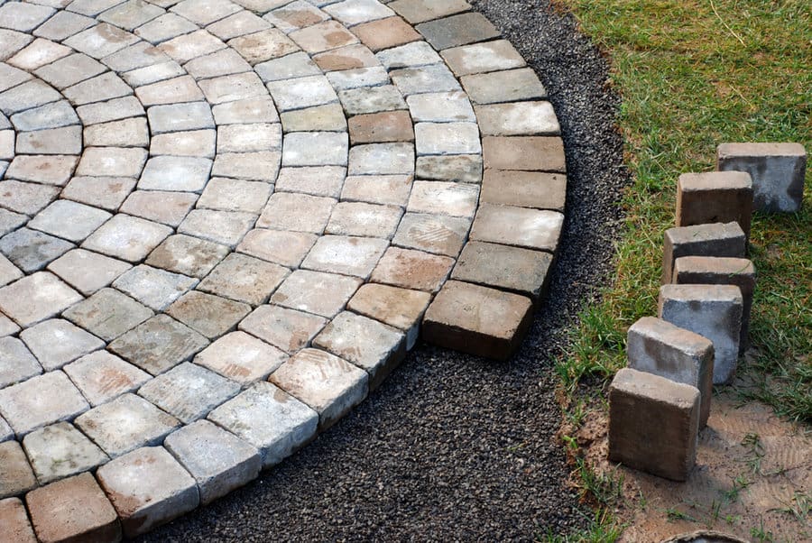 Partial view of a circular stone patio and curved paver edging